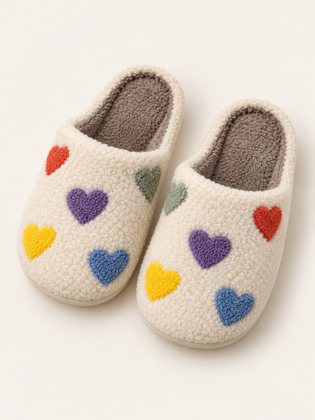 Pair of cream sherpa slippers with raised multicolored hearts and plush footbeds