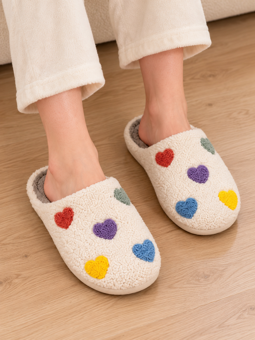 Adult wearing colorful heart sherpa house slippers in a home setting