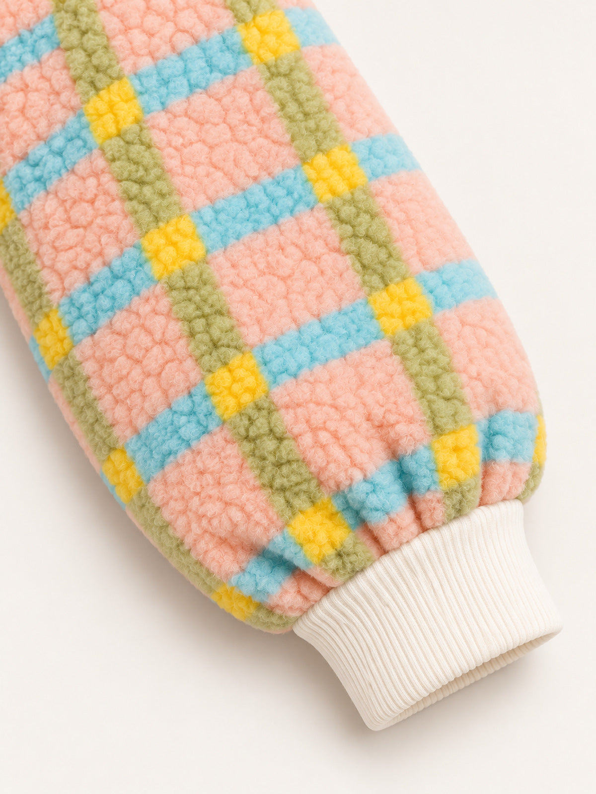 Close-up of a gathered sleeve and cream ribbed wrist cuff on the pastel plaid onesie