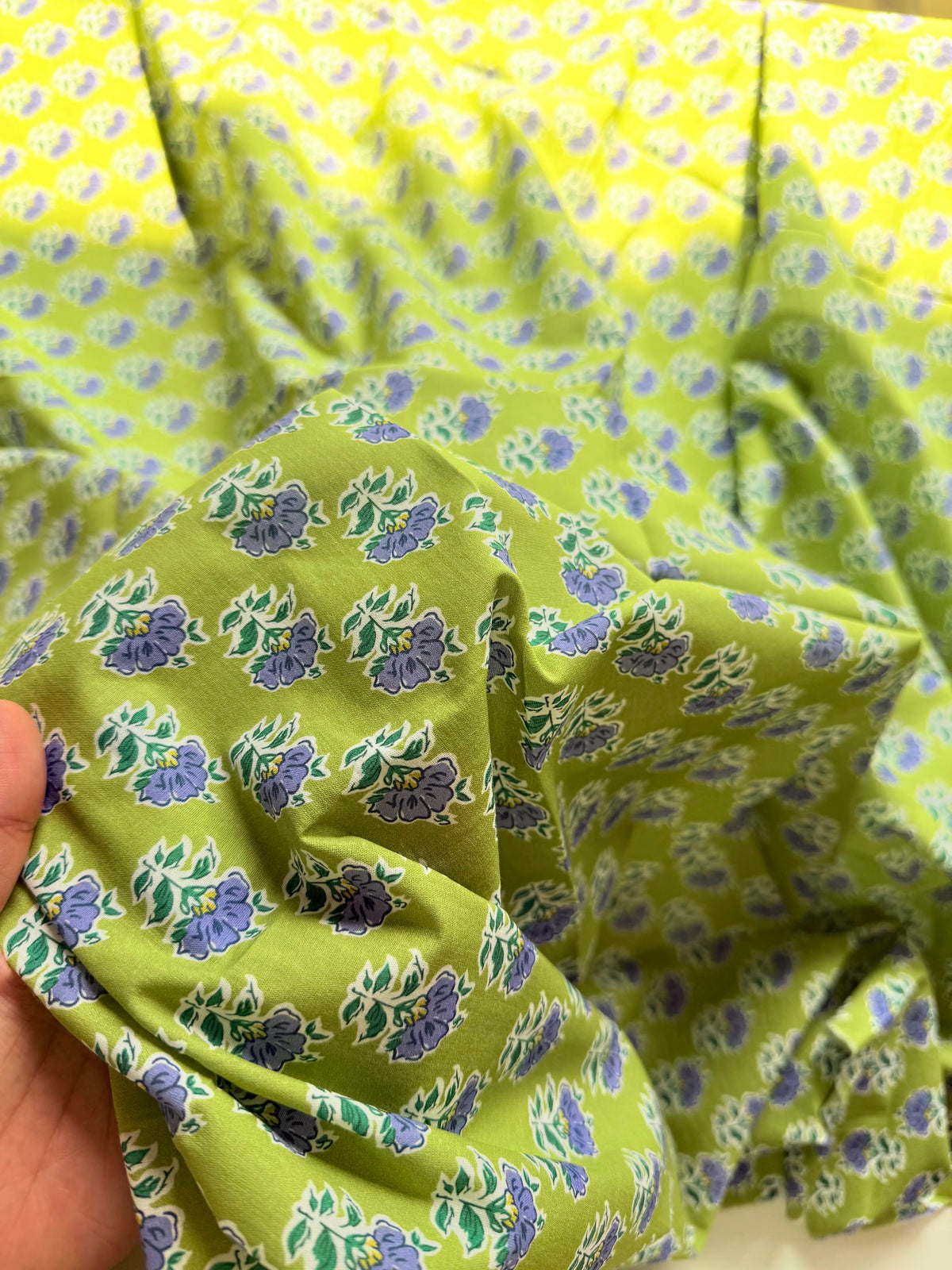 Close-up of blue and violet flowers with green leaves on lime-green fabric