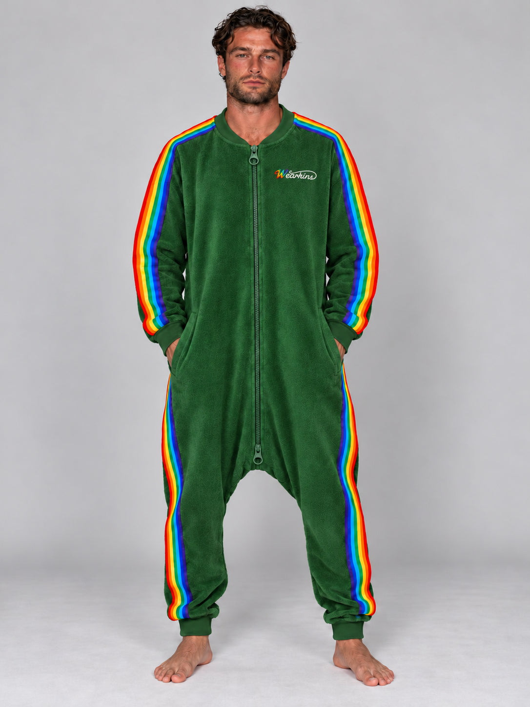 Adult man wearing the forest green rainbow stripe terry onesie with Wearkins chest embroidery and a matching green two-way zipper