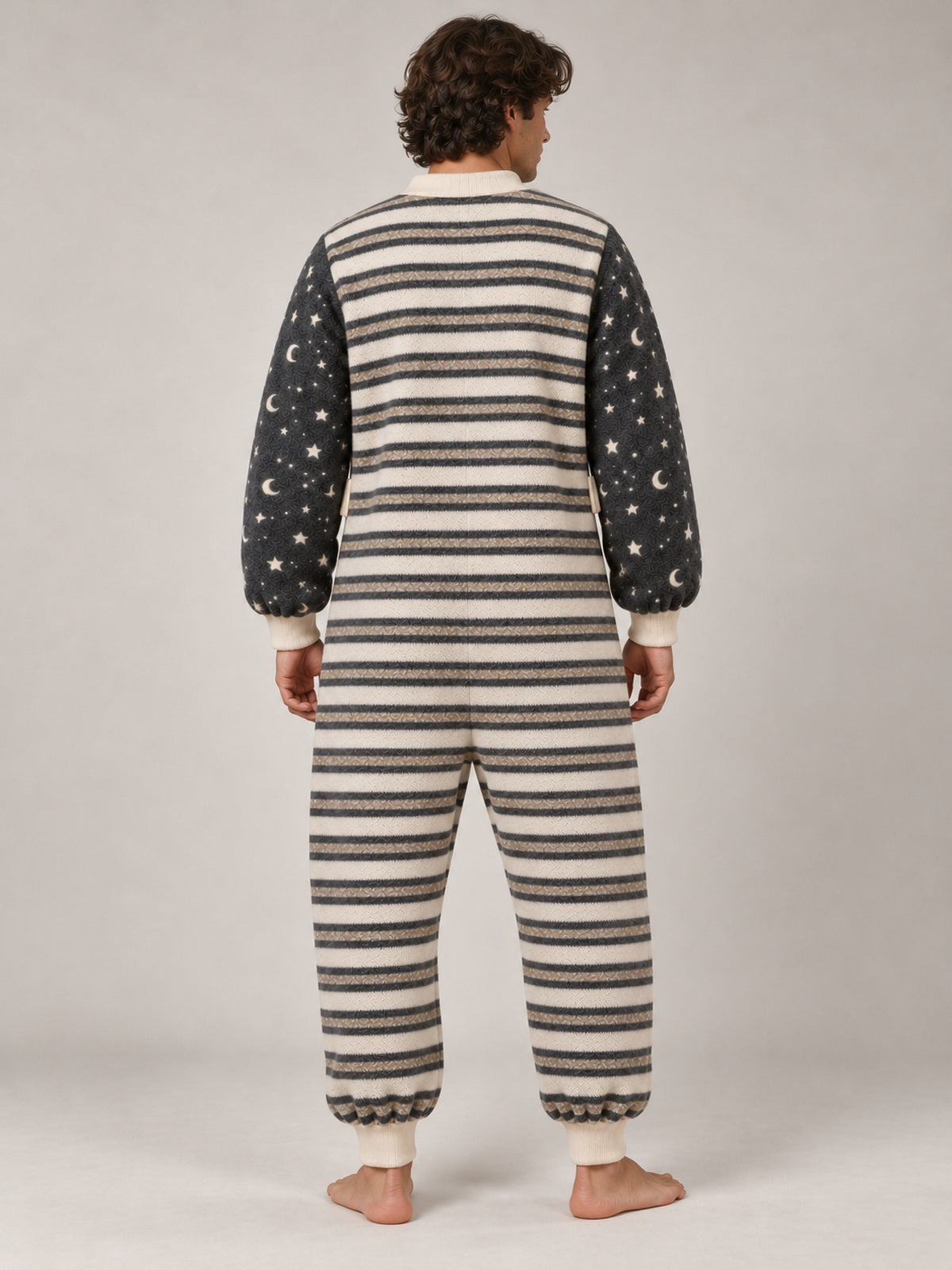 Full-length back view of an adult male model wearing the striped onesie with star and moon sleeves and cream ribbed cuffs
