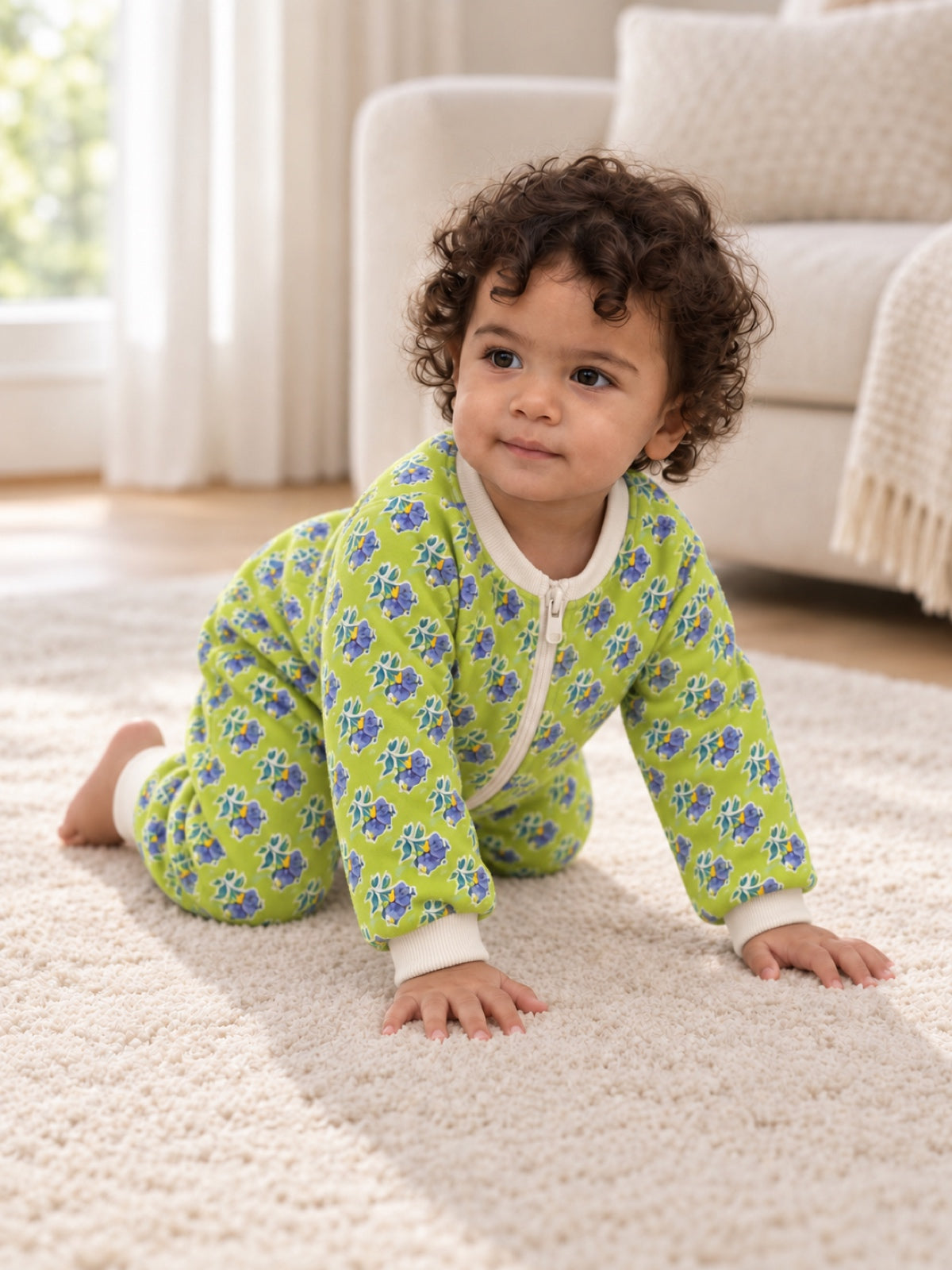 Baby wearing a lime-green floral onesie while crawling on a carpet