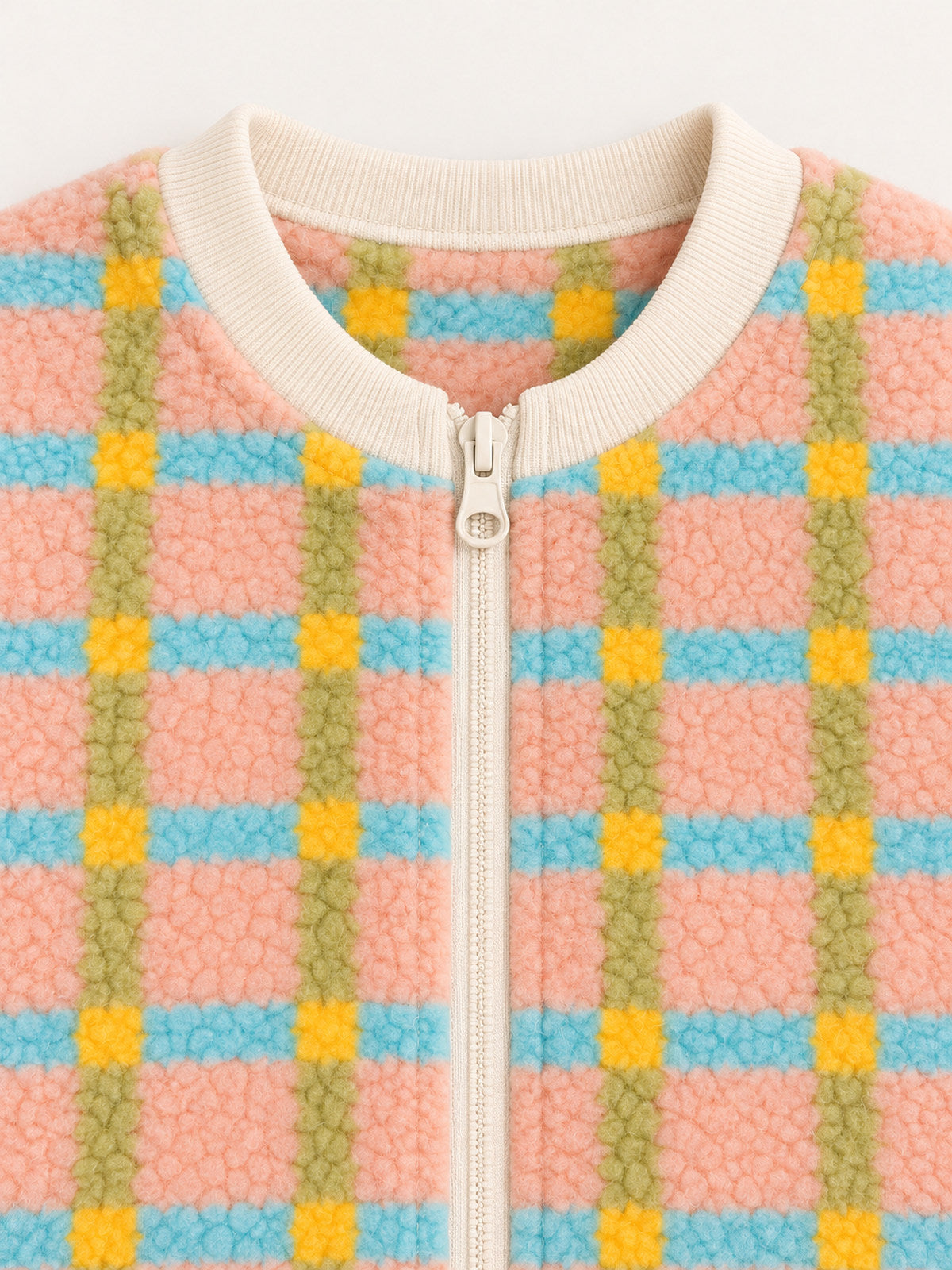 Close-up of the cream ribbed round neckline and upper ring-pull zipper on the pastel plaid onesie
