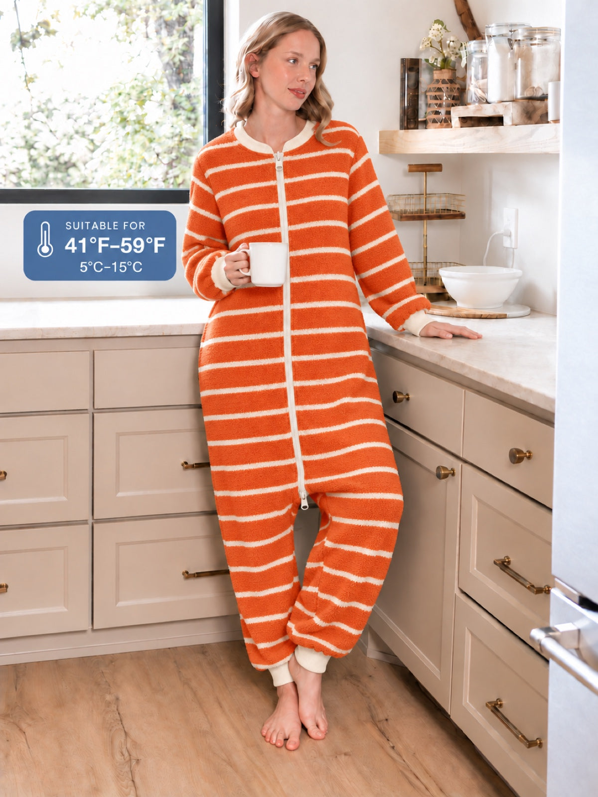 Adult model wearing an orange-and-ivory striped onesie in a kitchen