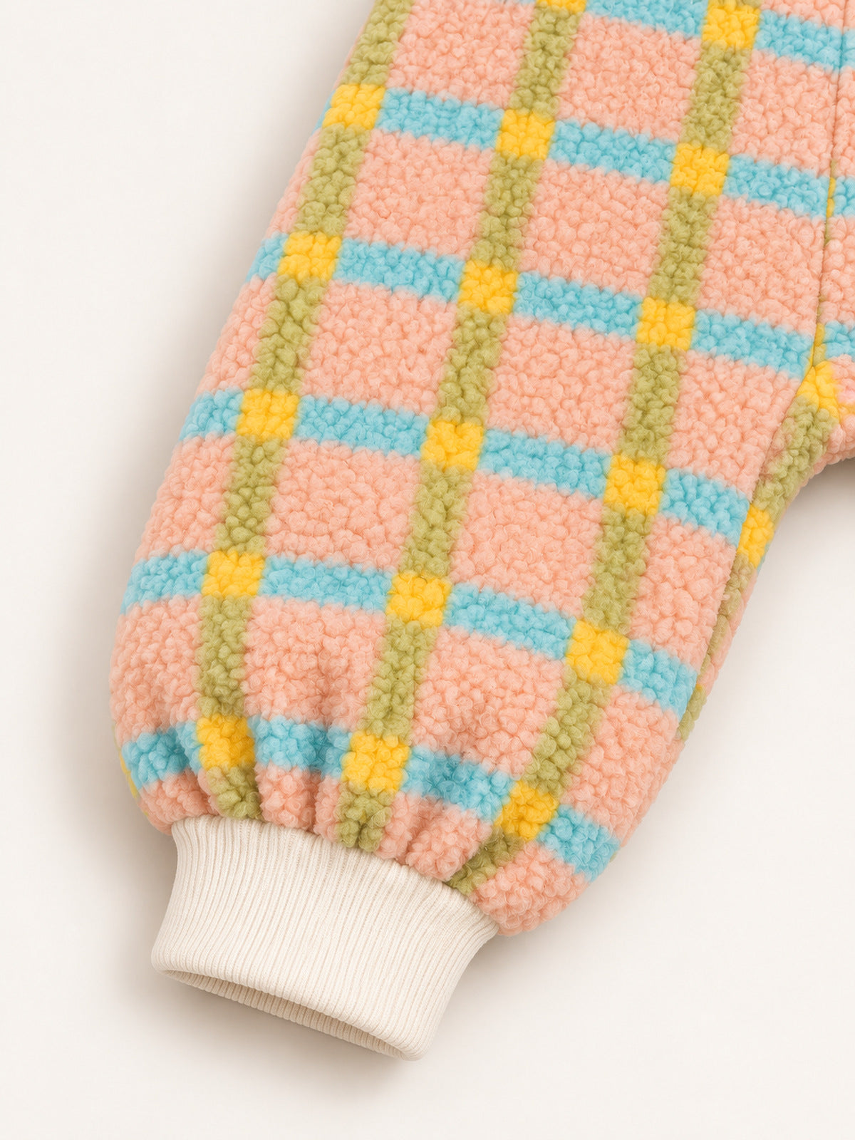 Close-up of the gathered leg and cream ribbed ankle cuff on the pastel plaid onesie