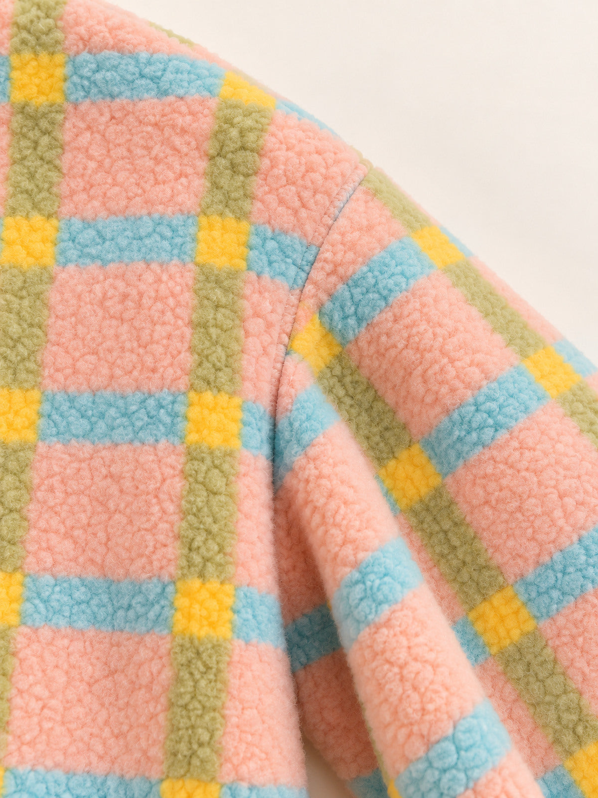 Close-up of the shoulder seam and colorful check pattern on the pastel plaid onesie
